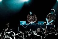 Дуэт Zeds Dead за пультом на сцене, перед ними тёмный зал с поднятыми руками